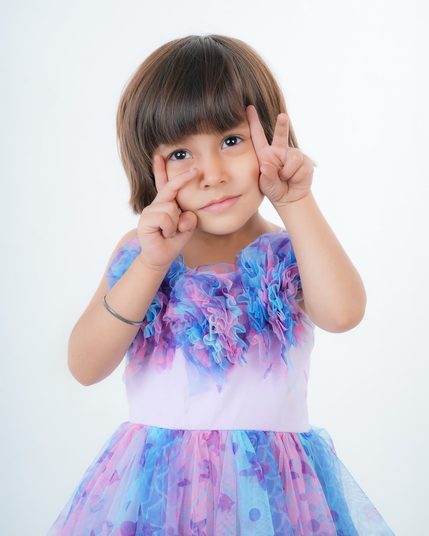 Close portrait of a young girl framing her face with both hands, smiling at camera