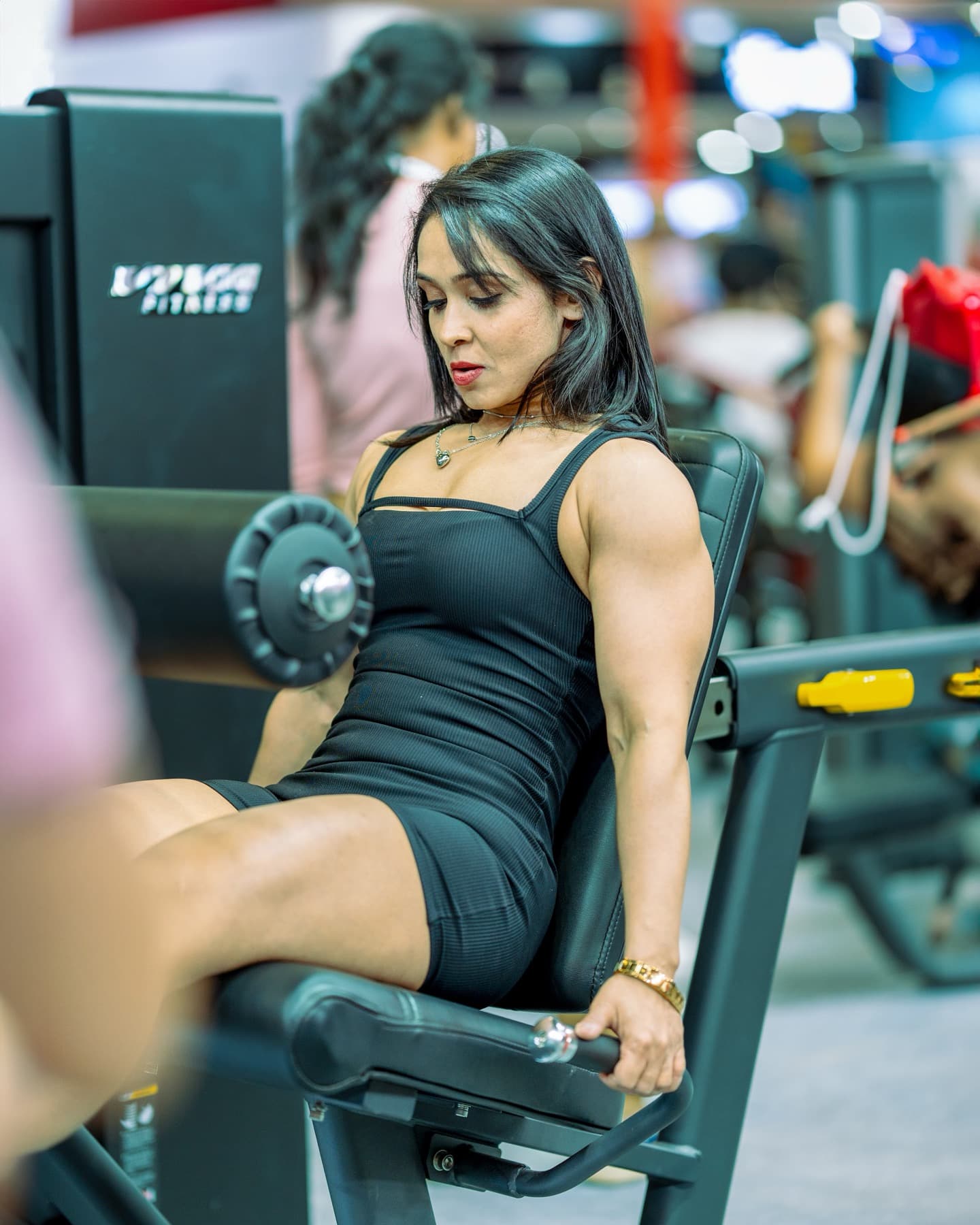 Woman in black gym wear performing a seated leg extension on a machine