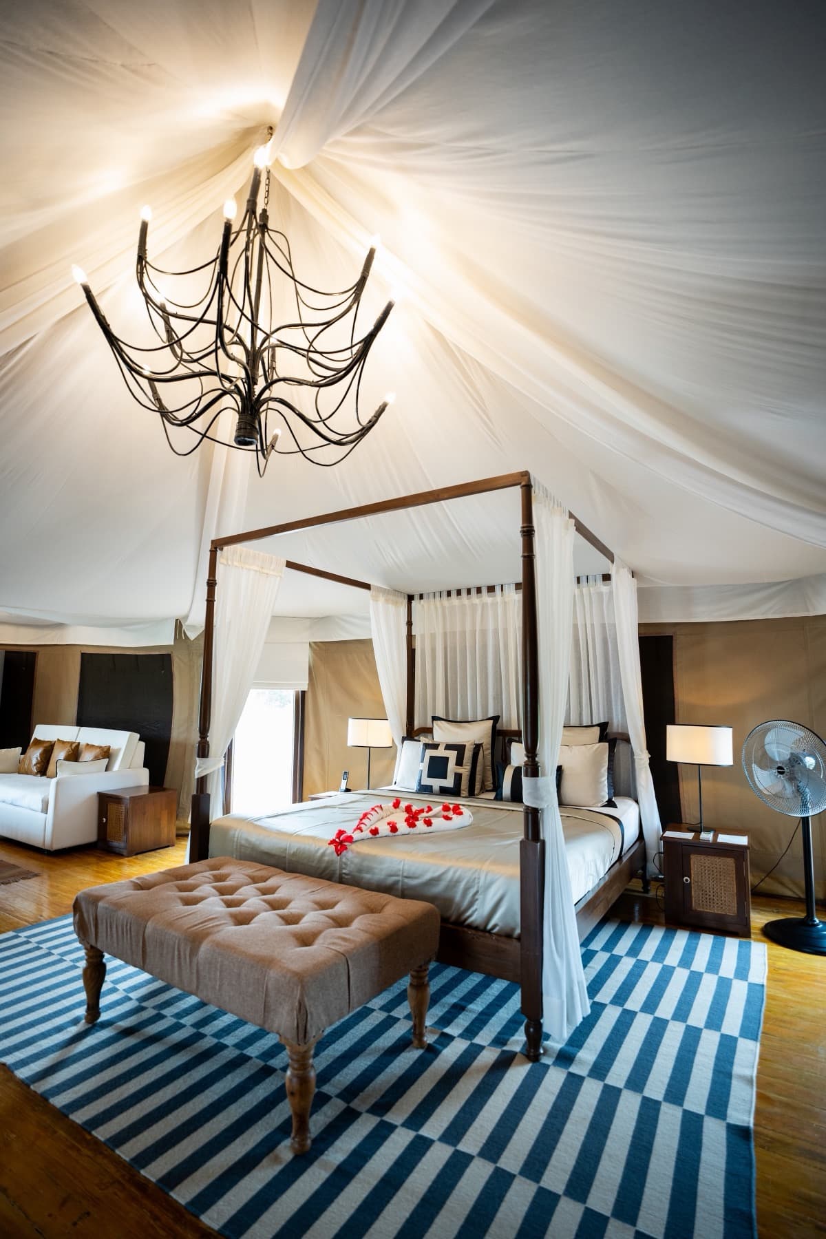 Four-poster canopy bed under a draped tent ceiling with an iron chandelier