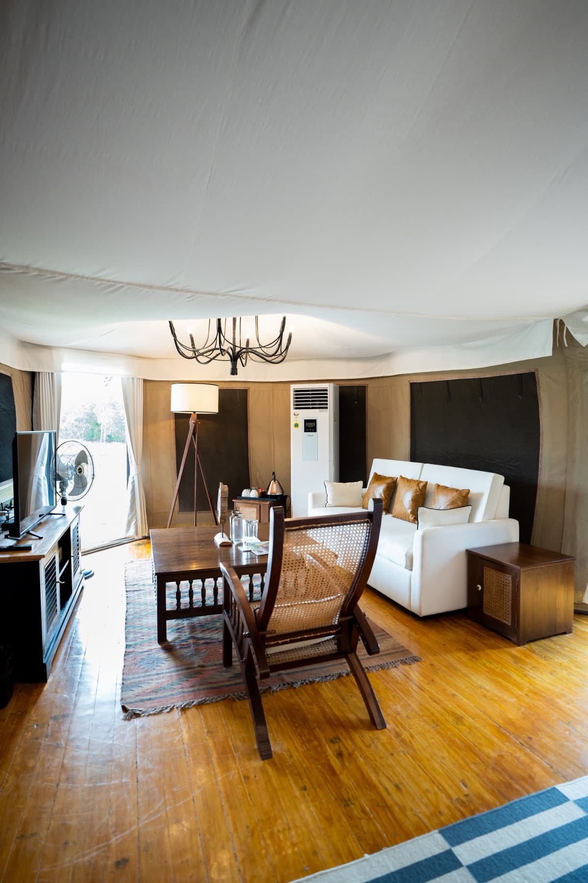 Sitting area of a tented suite with white sofa, planter chair and floor lamp