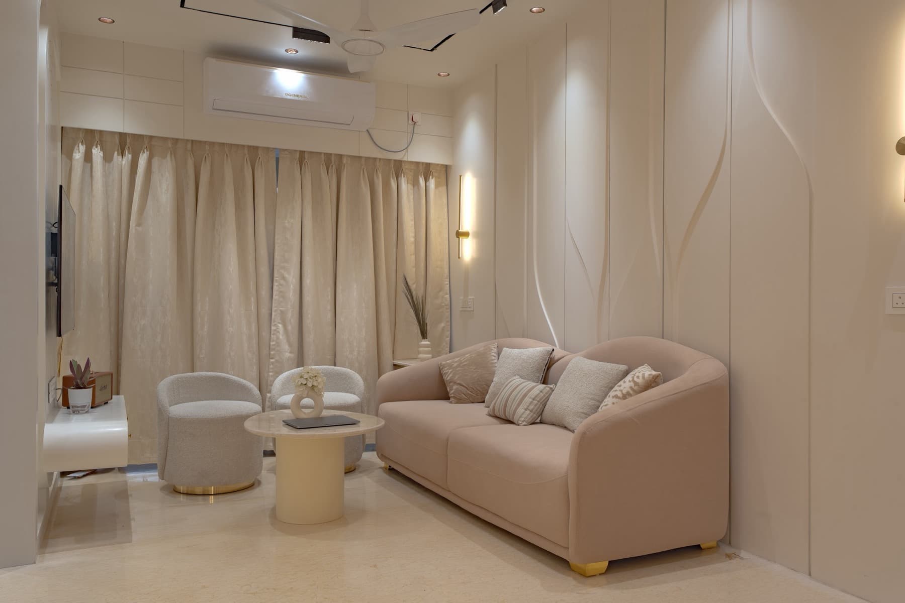 Blush sofa and two cream tub chairs around a round table in a pale living room