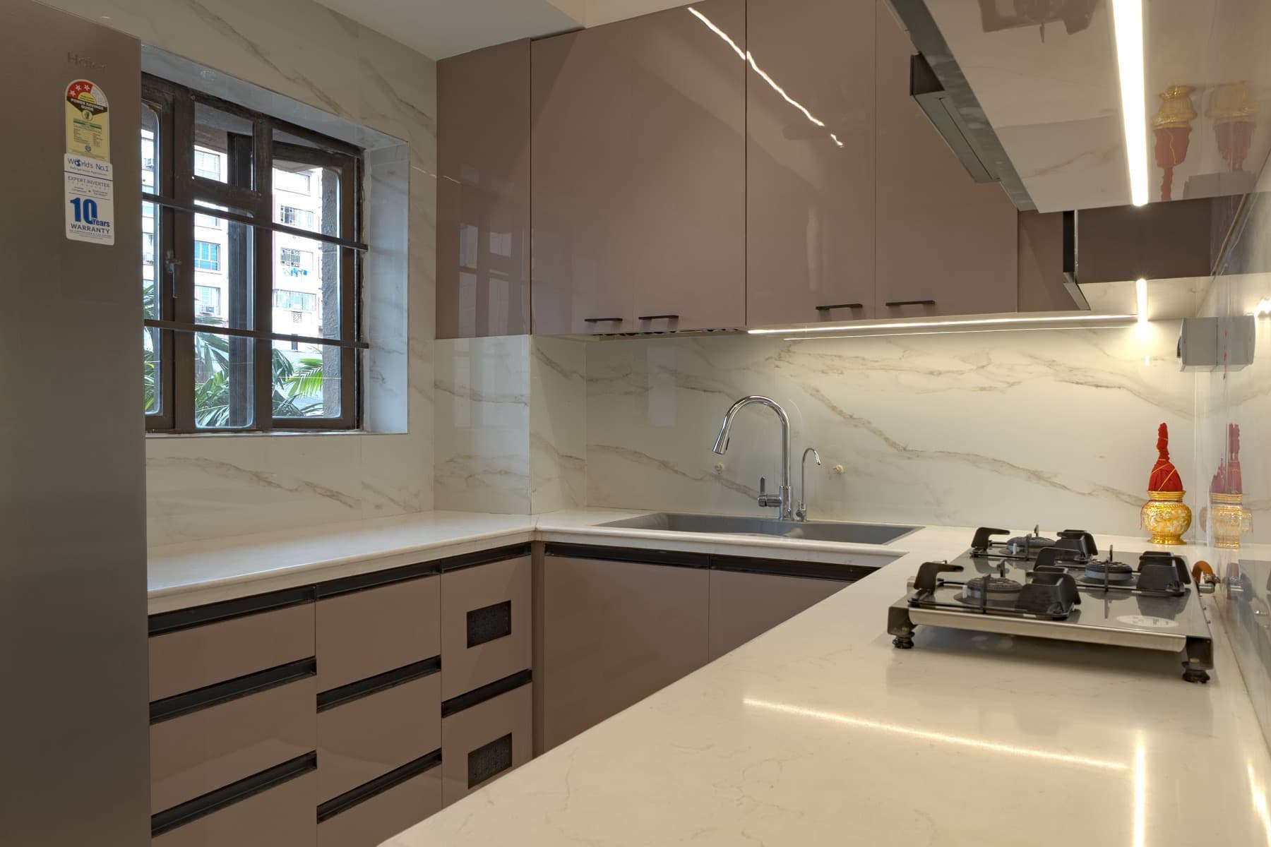 Kitchen corner with quartz counter, sink, gas hob and marble slab backsplash by a window