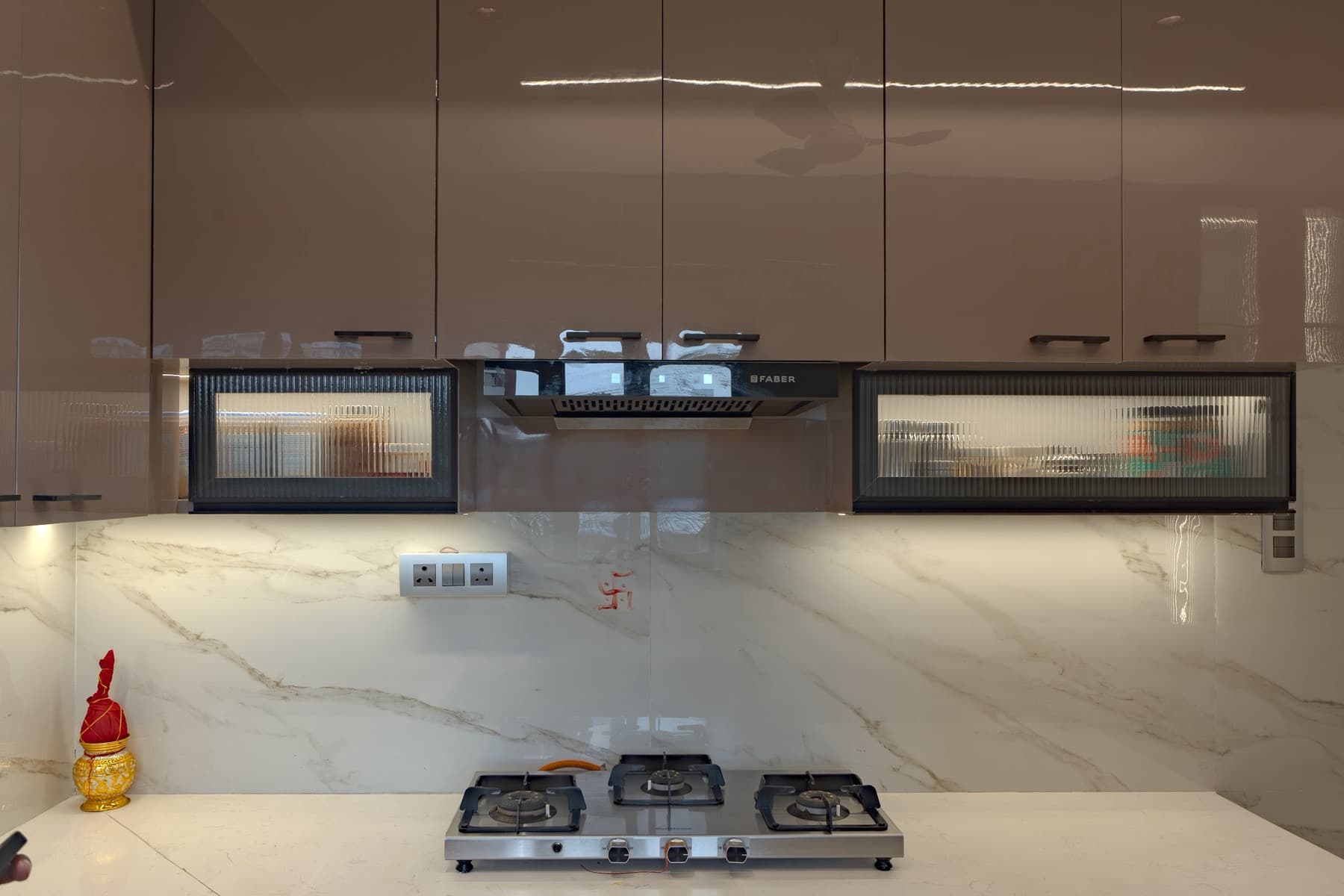Frontal kitchen wall with chimney hood, fluted-glass cabinets and three-burner gas hob