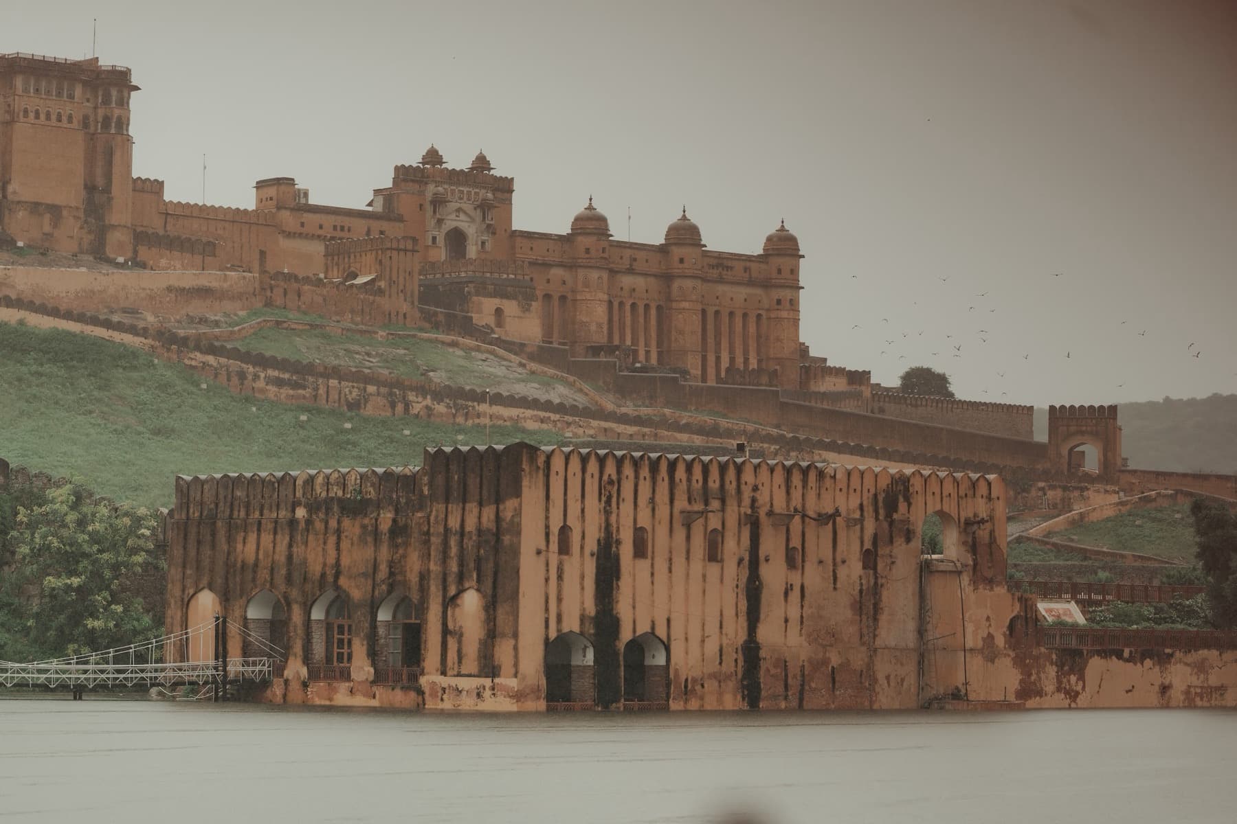 Hilltop fort above a weathered arcaded wall across flat grey water