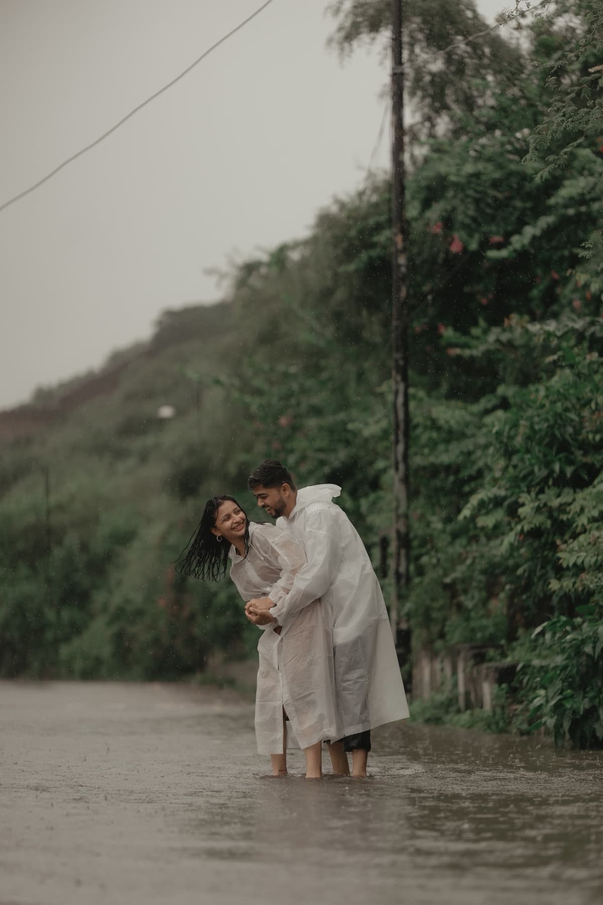 Couple embracing ankle-deep in floodwater on a misty hill road