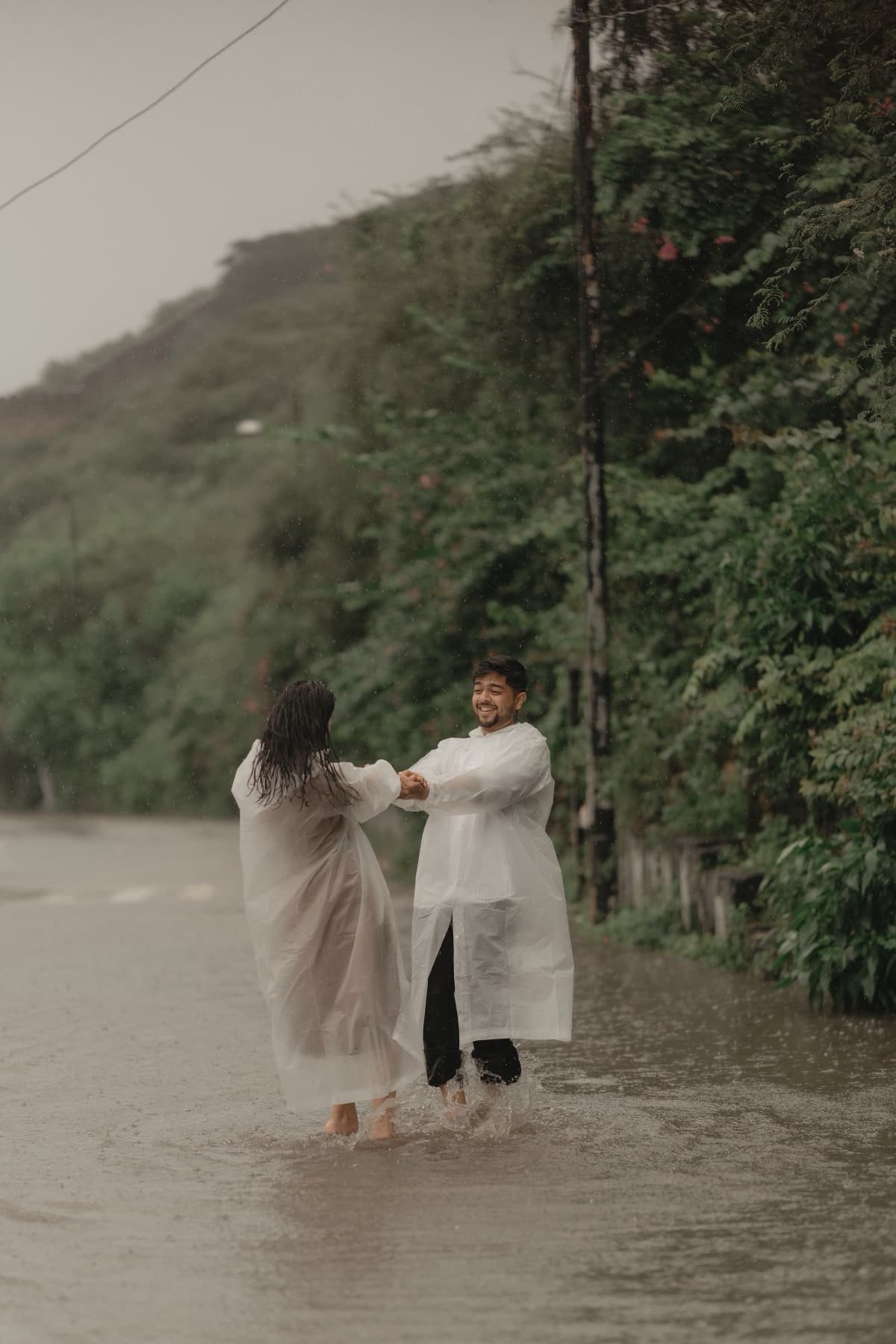 Couple holding hands facing each other in floodwater on a hill road
