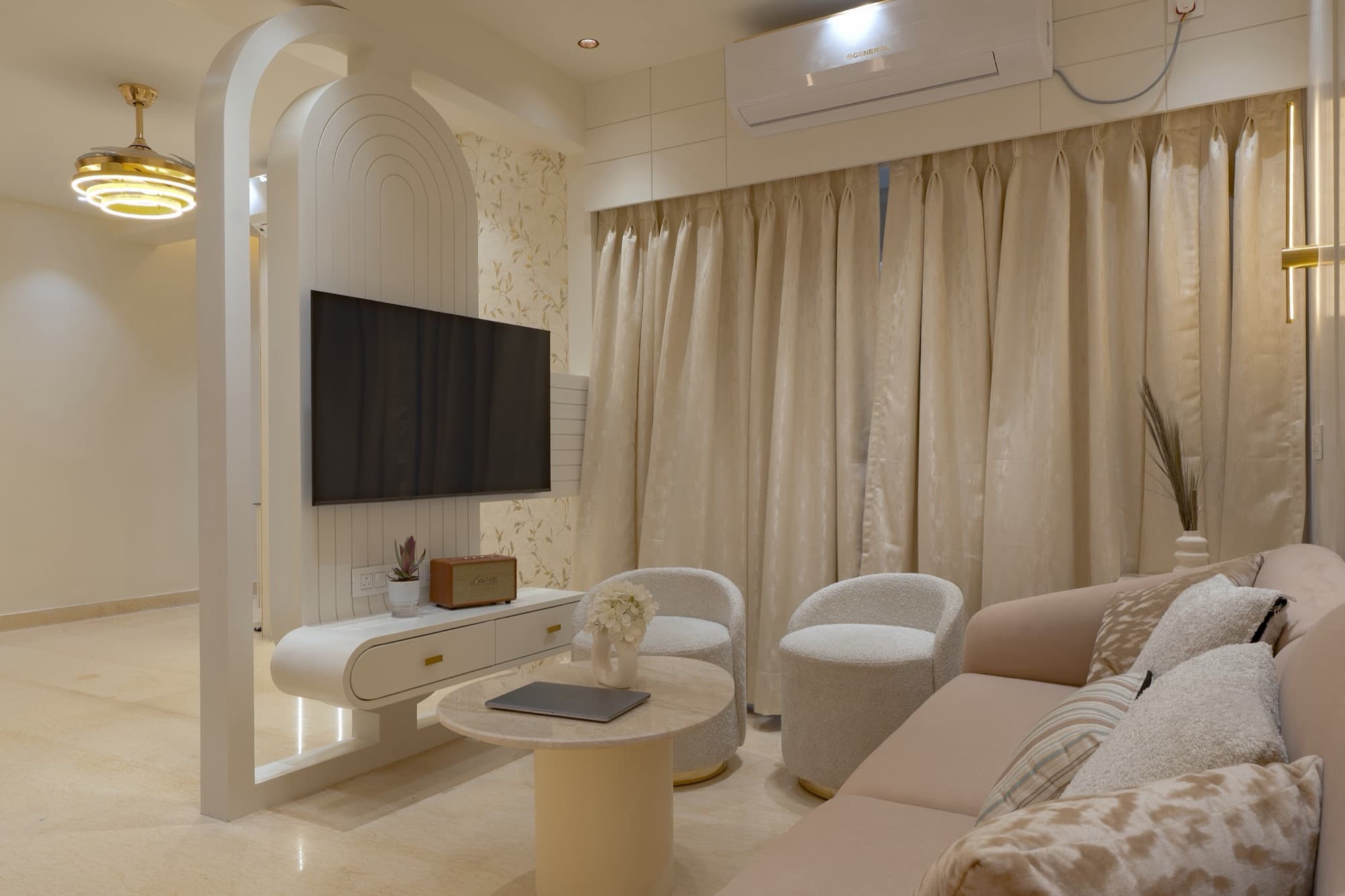 Living room with arched partition, wall-mounted TV, blush sofa and boucle tub chairs